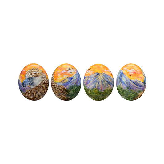 Set of five oval stones with mountain landscapes painted on them, arranged in a row.